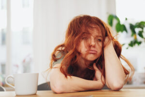 Eine Frau sitzt am Tisch und ist gestresst. Stress ist ein Zustand, den jeder kennt. Doch was ist Stress?